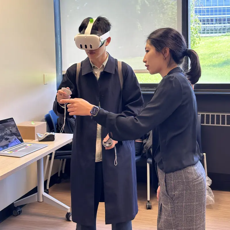 A presenter instructs a participant how to use a VR headset during a demo of learning technology